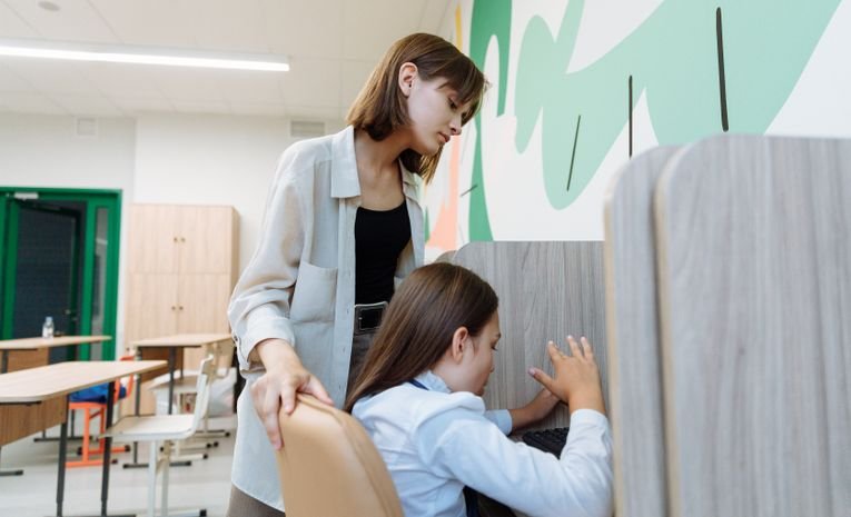 A teaching assistant helping a student in a classroom